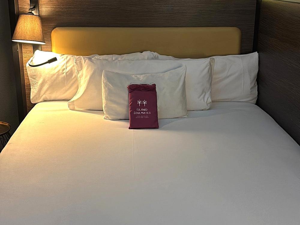 Toalla Island Soulmates como regalo de bienvenida sobre la cama de una habitación de hotel